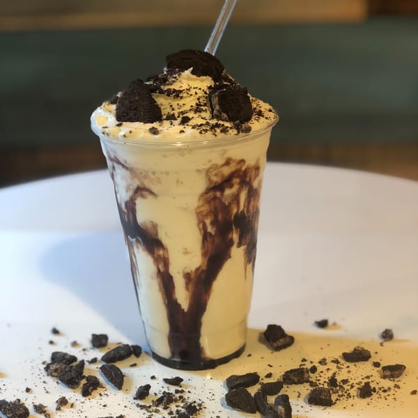 P.S. Burgers' cookies and cream milkshake, topped with whipped cream and cookie crumbles, on a white table.